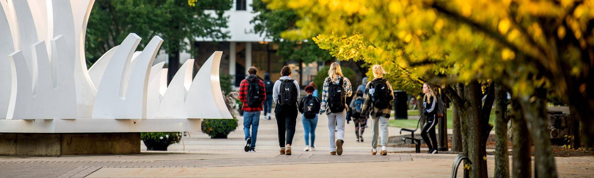 Students walking next to Heaven and Earth sculpture towards Lake Huron Hall